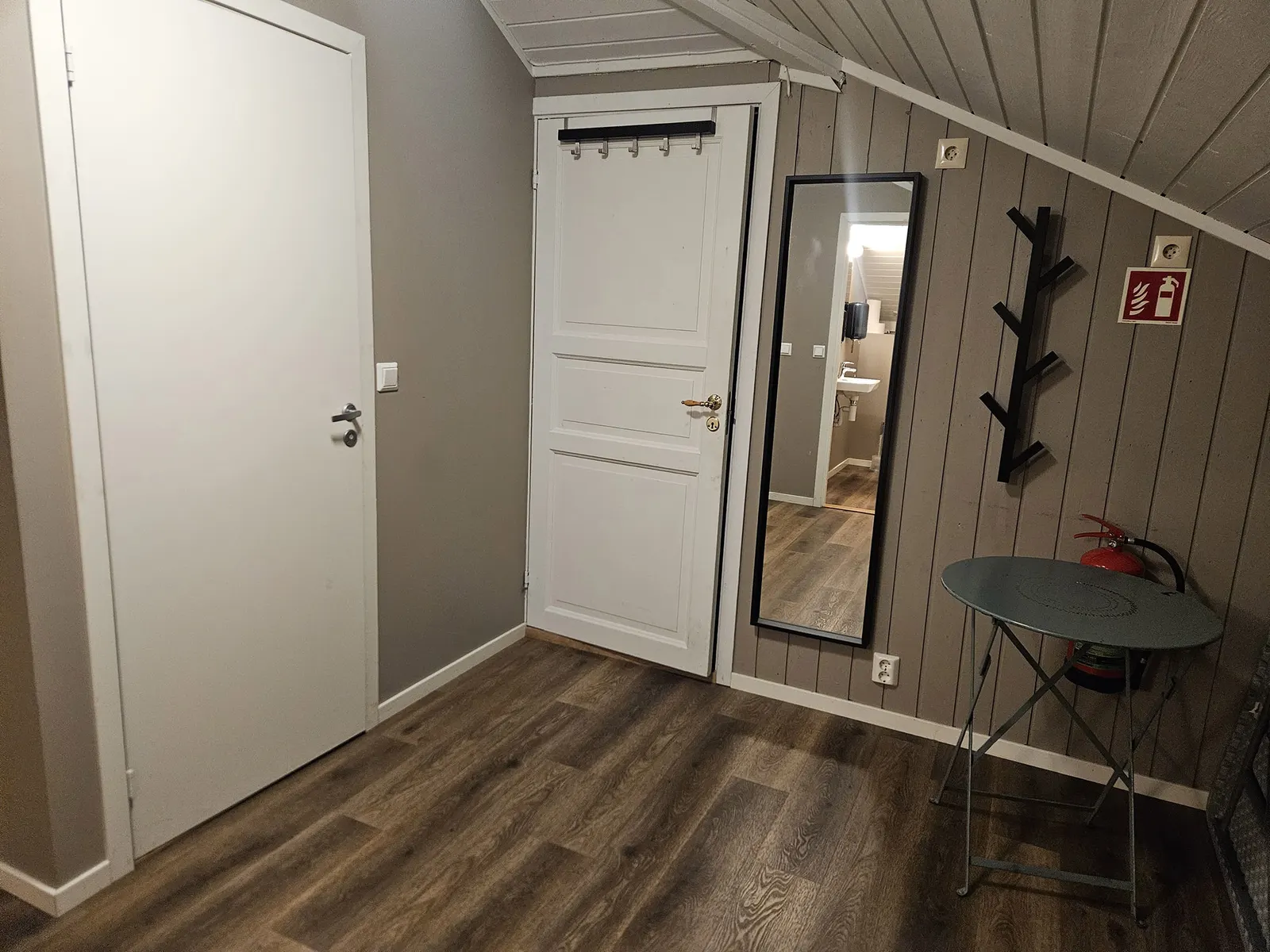 Inngangspartiet i Hallen med speil, knagger og et lite bistrobord
